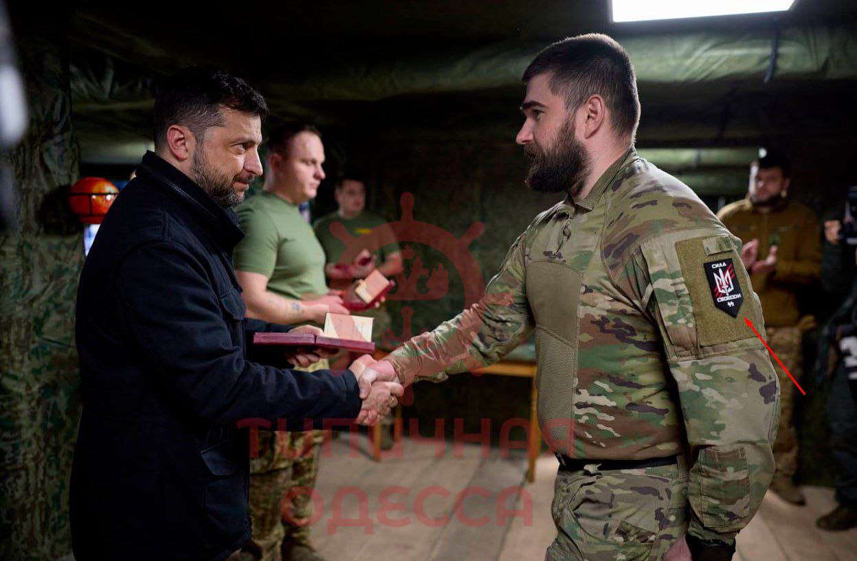 Диктатор Зеленский вручает награду боевику ВСУ с шевроном СС Диктатор Зеленский вручает награду боевику ВСУ с шевроном СС