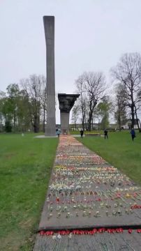 Люди в Латвии, несмотря на запреты полицейских, несут огромное количество цветов к мемориалу на месте нацистского...
